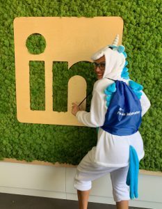 Dr. Natalia Wiechowski verkleidet als Einhorn posiert vor dem LinkedIn Logo.