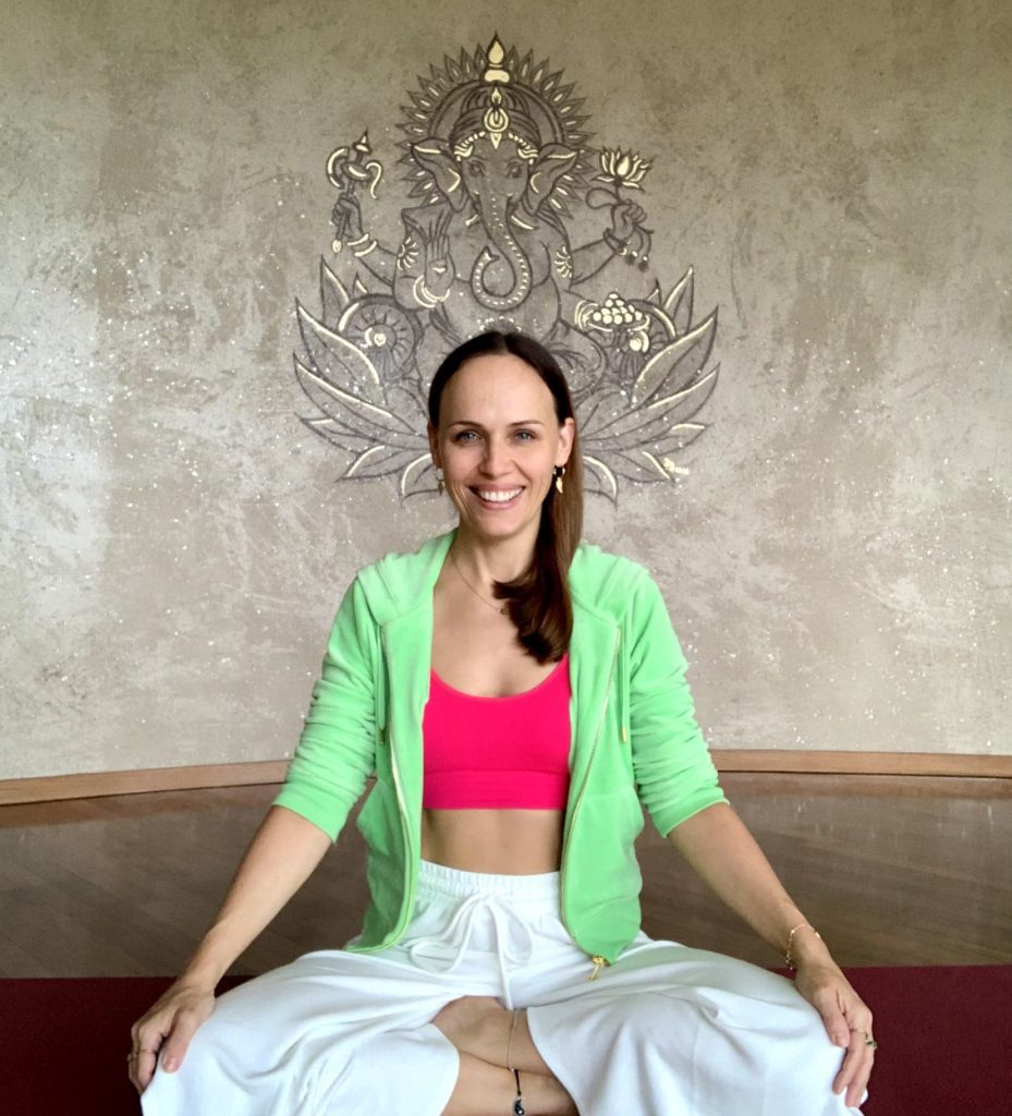 Dr. Natalia Wiechowski sitzt in einer Yoga-Pose und lächelt in die Kamera.