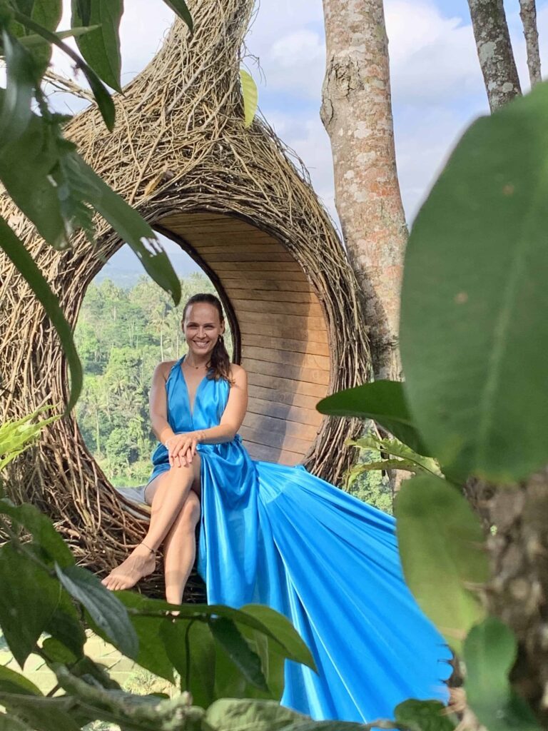 Dr. Natalia Wiechowski sitting in a giant wooden hole wearing a blue dress.