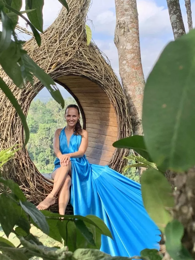 Dr. Natalia Wiechowski sitting in a giant wooden hole wearing a blue dress.